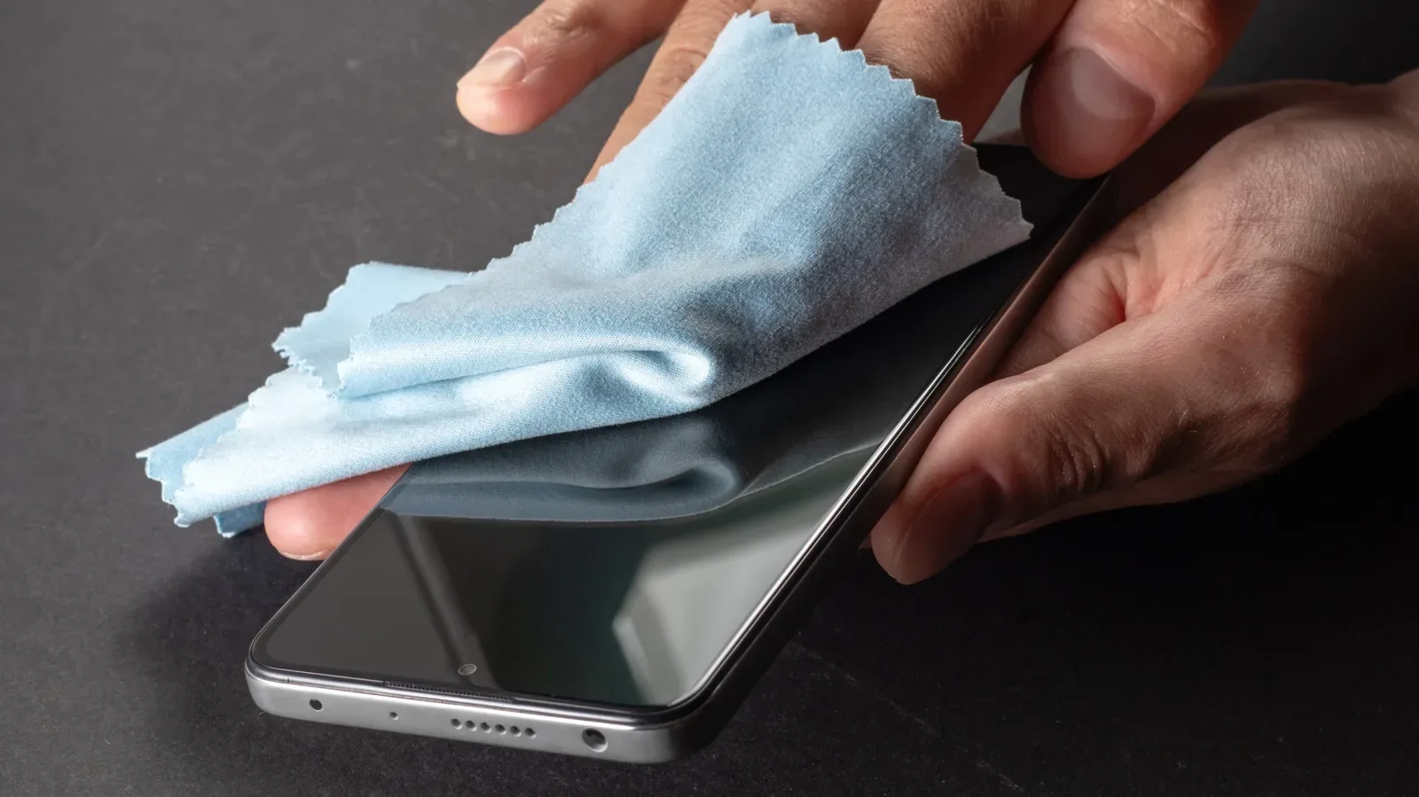 A smartphone being gently wiped with a lint-free microfiber cloth
