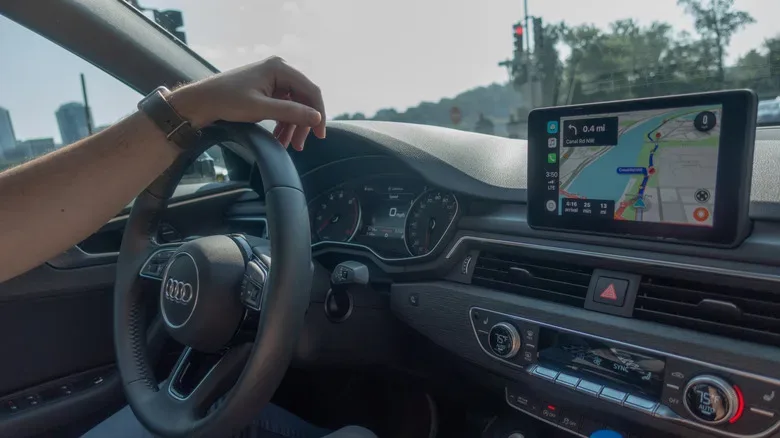 Driver checking a compact portable CarPlay display in an older car interior