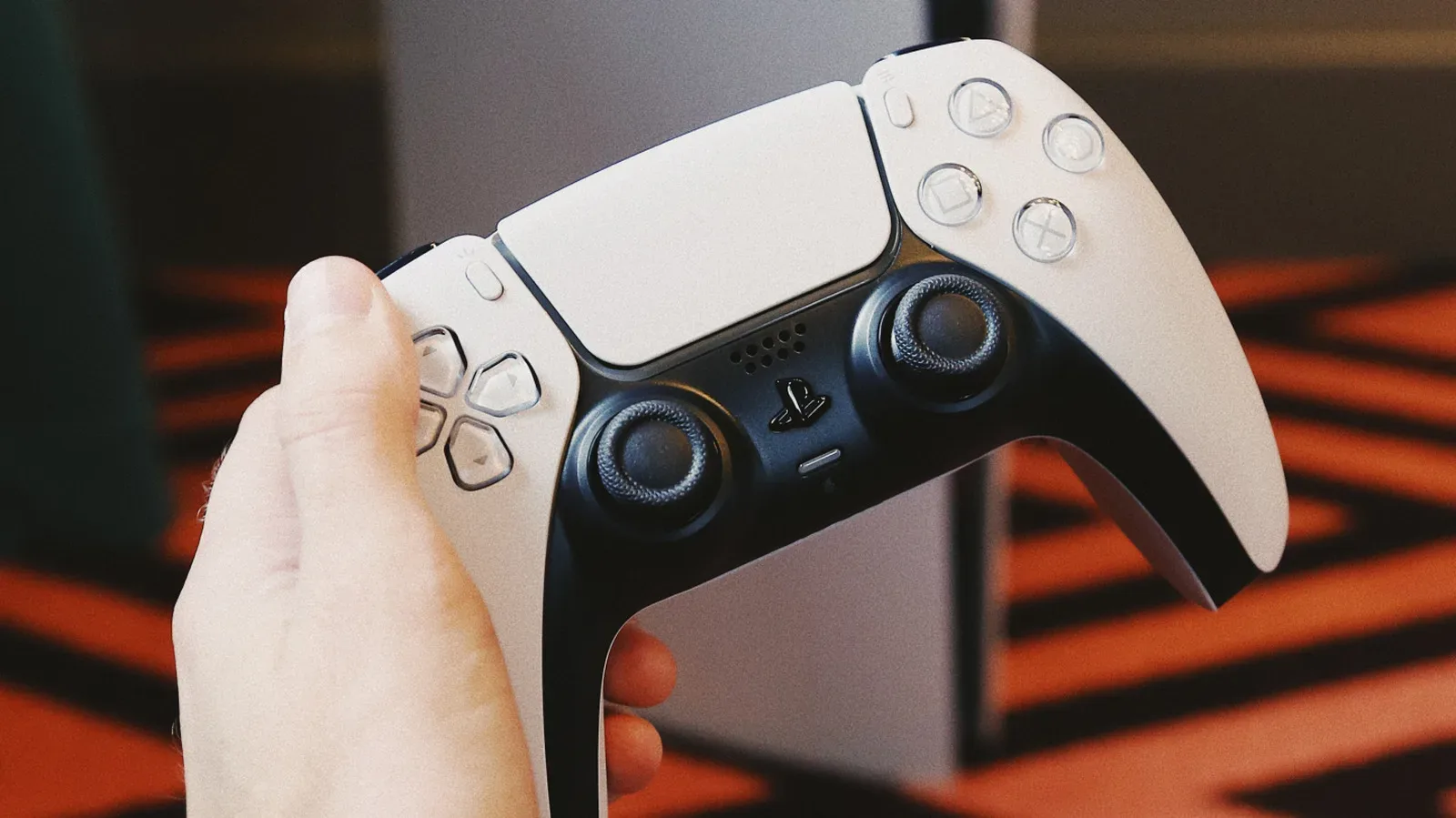 A white PS5 DualSense controller beside a USB-C charging cable