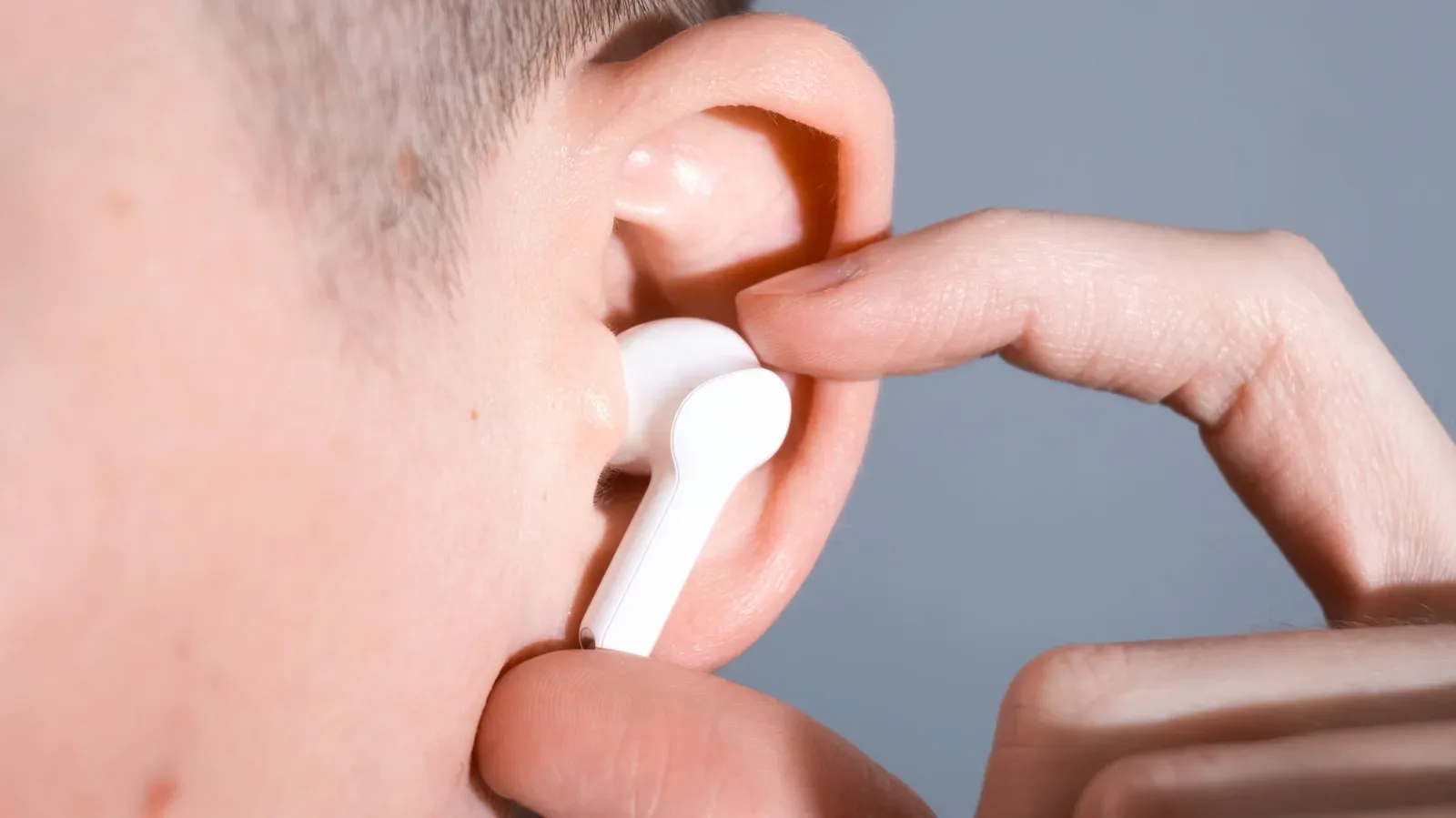A person wearing wireless translation earbuds while using a smartphone translation app