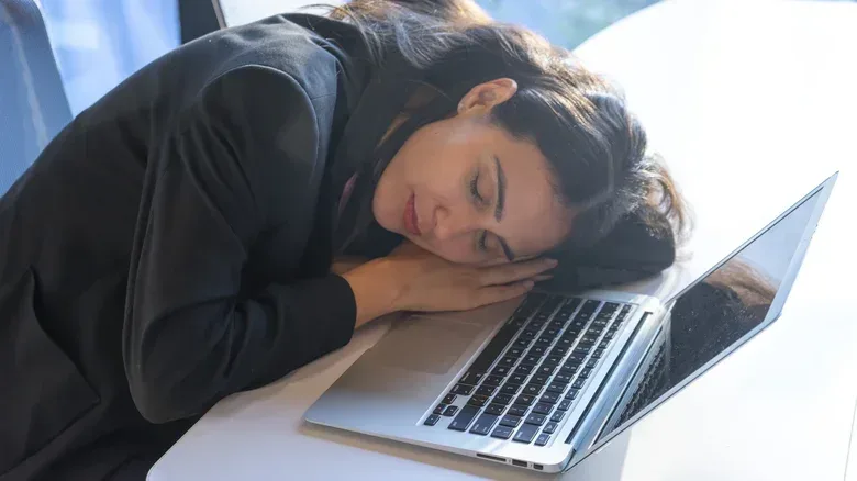 Woman sleeping at a table in front of a MacBook.