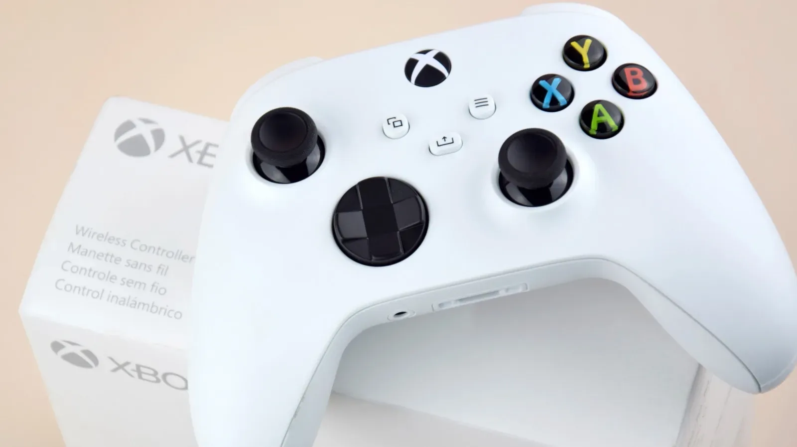 An Xbox controller connected by USB cable beside a console