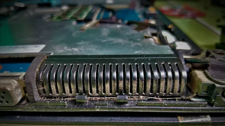 Electronics-safe compressed air being used in short bursts near a laptop vent