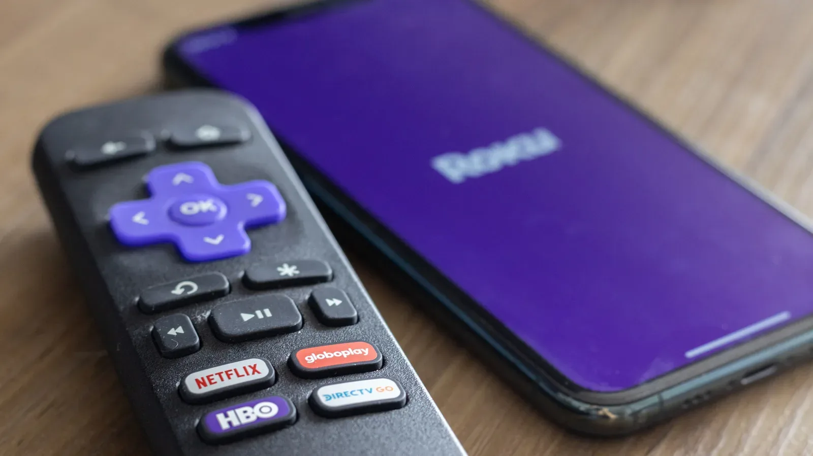 A Roku remote beside a television displaying the Roku home screen