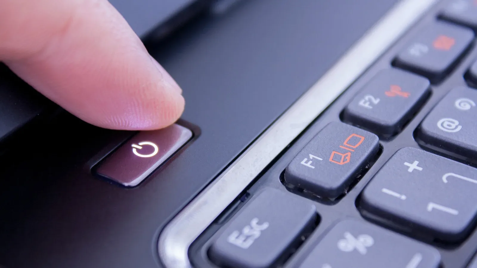 A desktop PC power button beside a gaming keyboard