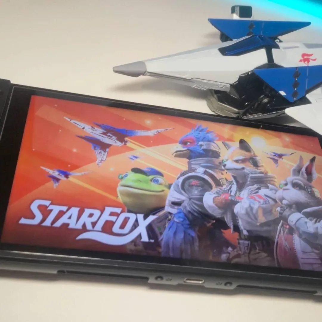 Photo of the key art for Star Fox showing on a Nintendo Switch 2, with a toy Arwing sitting above.