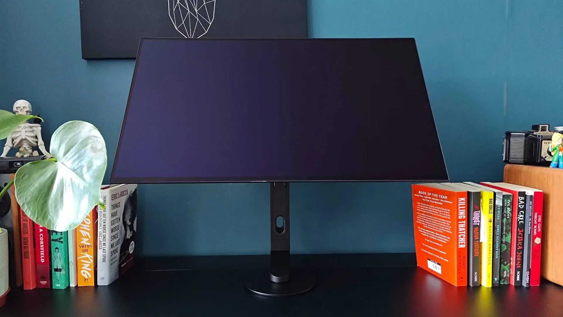 Sony Inzone M10S II on black desk next to books with panel tiled back.