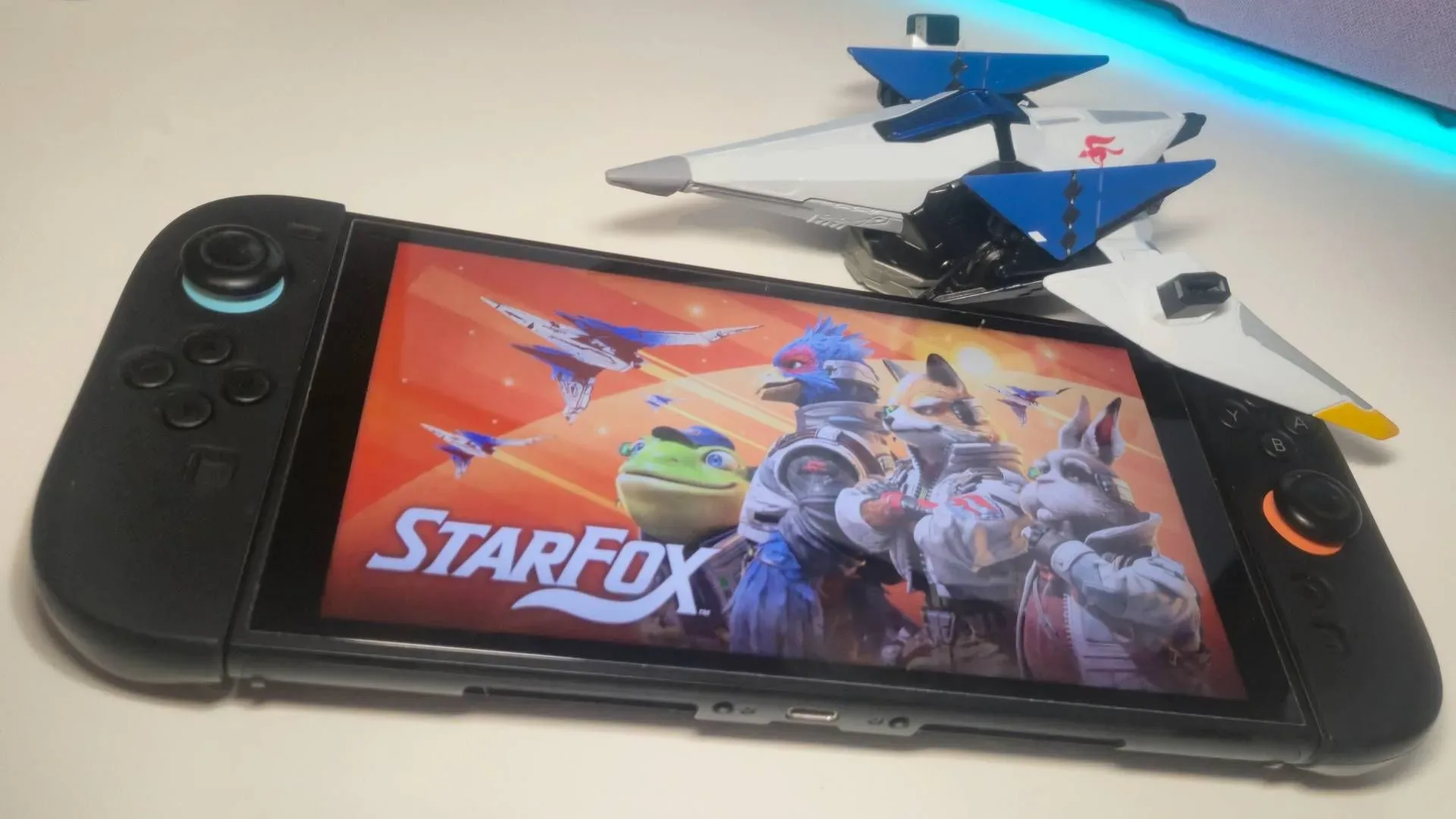 Photo of the key art for Star Fox showing on a Nintendo Switch 2, with a toy Arwing sitting above.