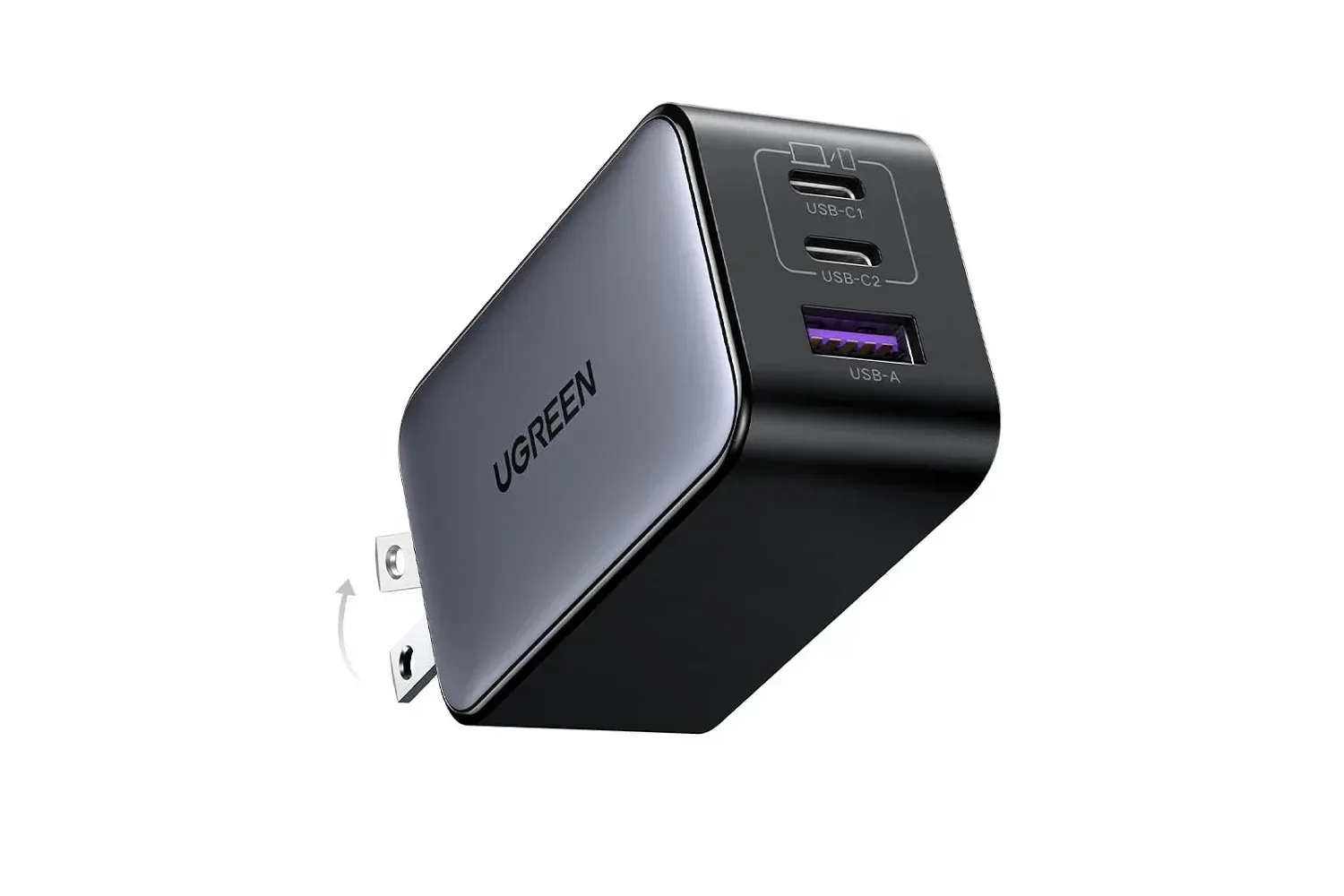 UGREEN Nexode 65W three-port charger on a desk beside a phone, earbuds and laptop