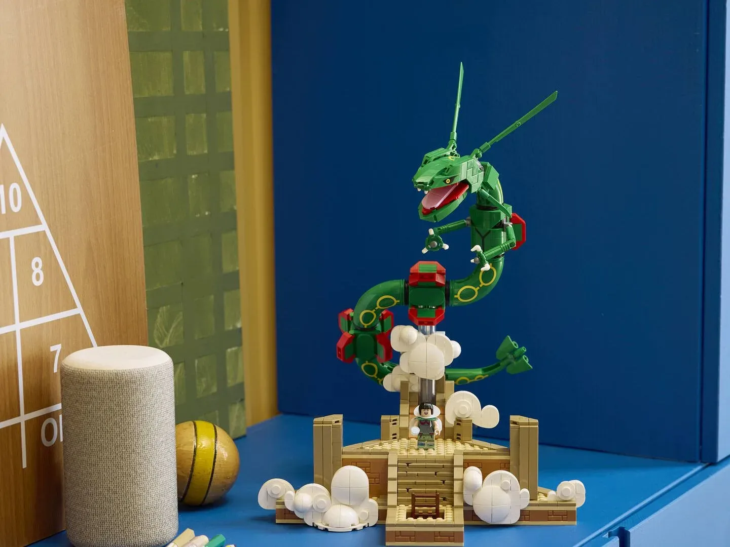 Lego Rayquaza set on a blue sideboard, with a triangle of numbers on a wall beside it