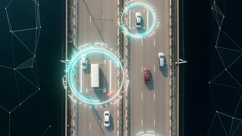 Overhead view of vehicles on a highway, with digital tracking graphics around several cars.