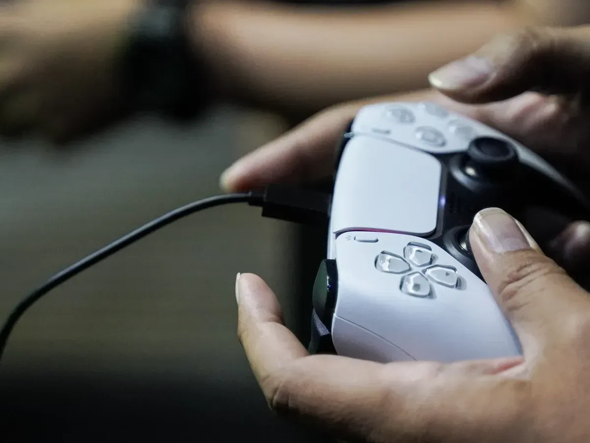 A bank card held near a game controller to illustrate contactless console payments