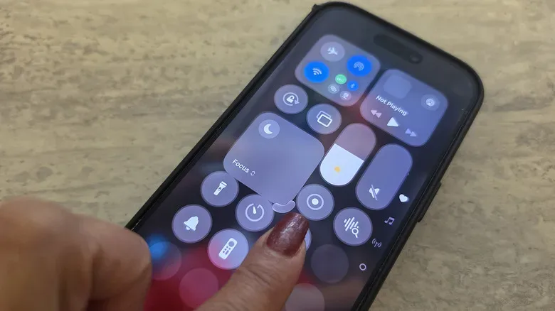 A finger dragging on the Focus mode icon in Control Center on iPhone to make it bigger.