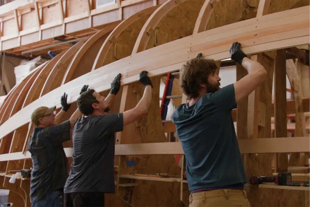 Workers shape timber during the construction of the yacht Kiandra at Brooklin Boat Yard