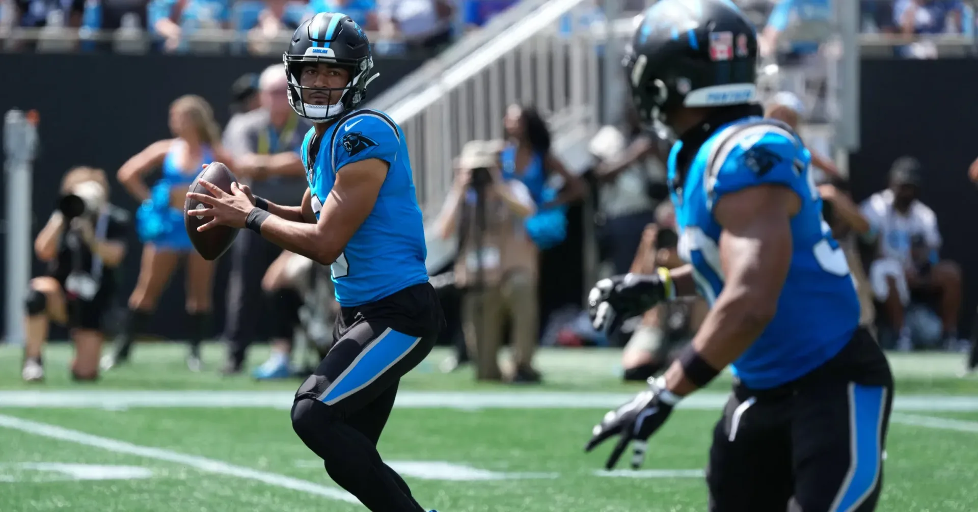 Bryce Young wearing blue and black Air Jordan 10 Low PE cleats with Panthers uniform colors