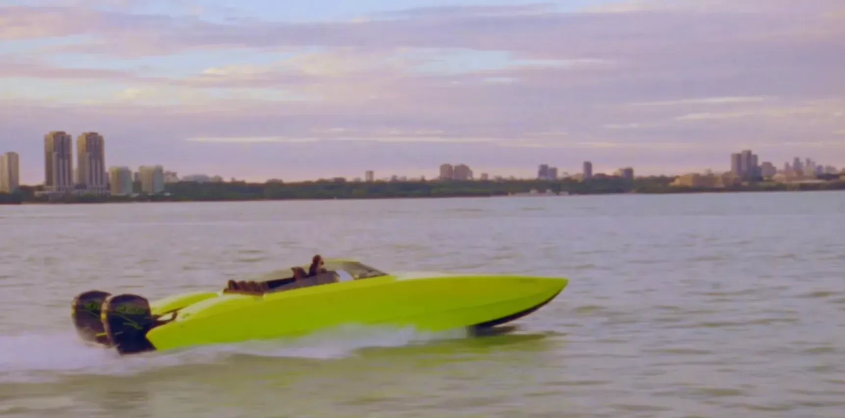 A neon-green speedboat crossing calm ocean water in Drake’s Fear of Missing Out teaser