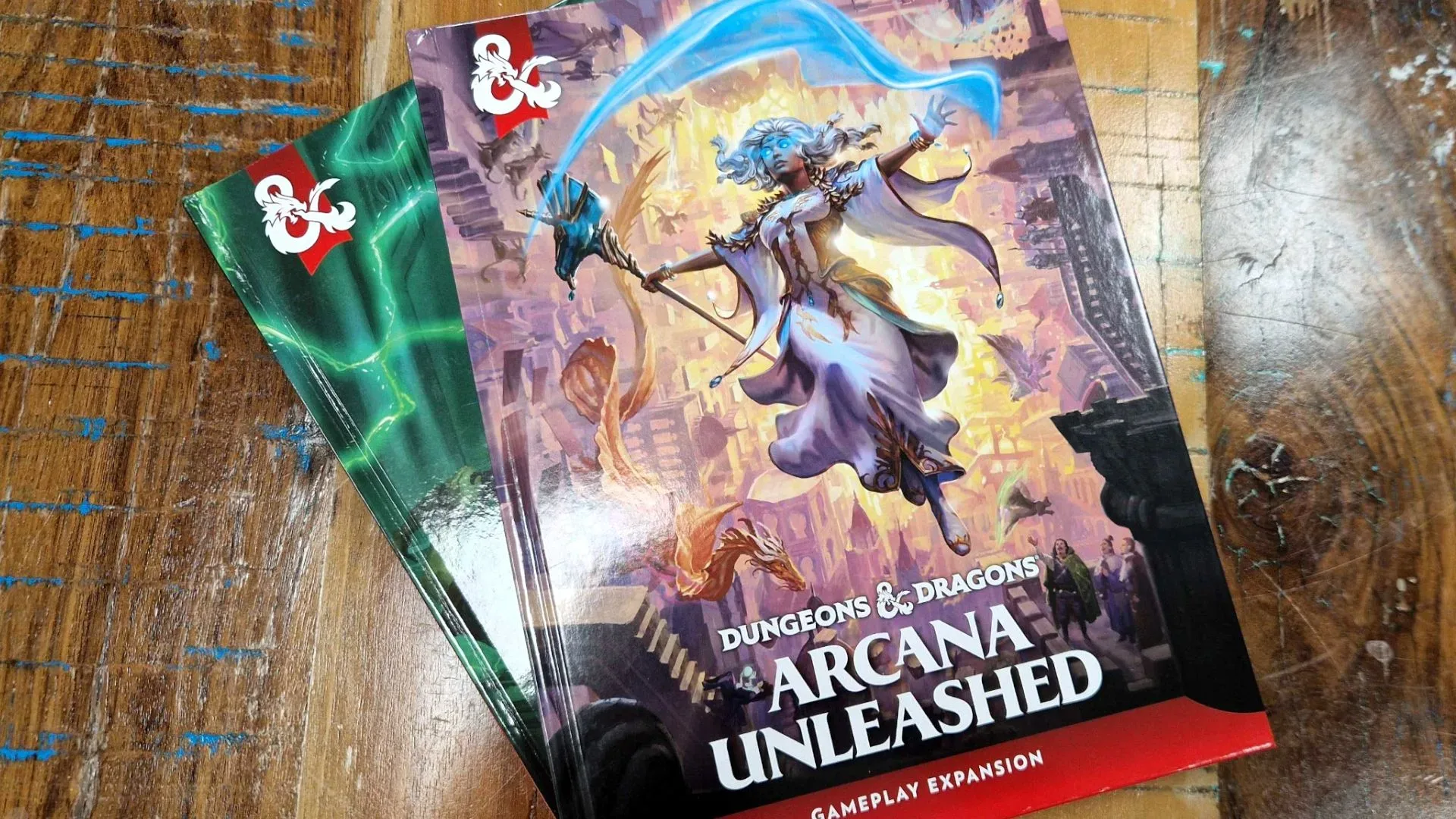 D&D Arcana Unleashed and Deadfall books stacked atop one another, on a wooden surface