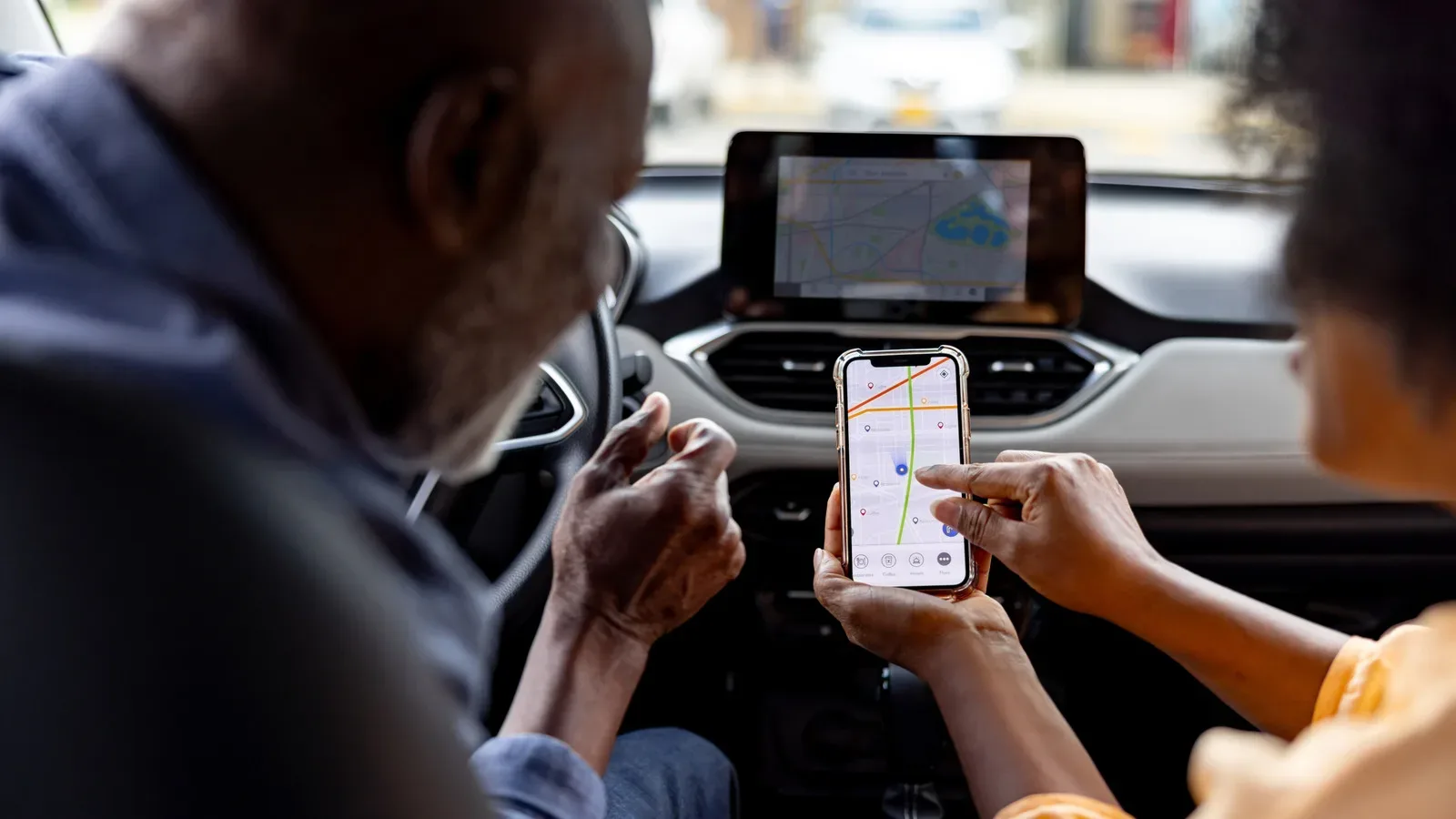 A car infotainment display showing Apple CarPlay while two iPhones are paired to the vehicle