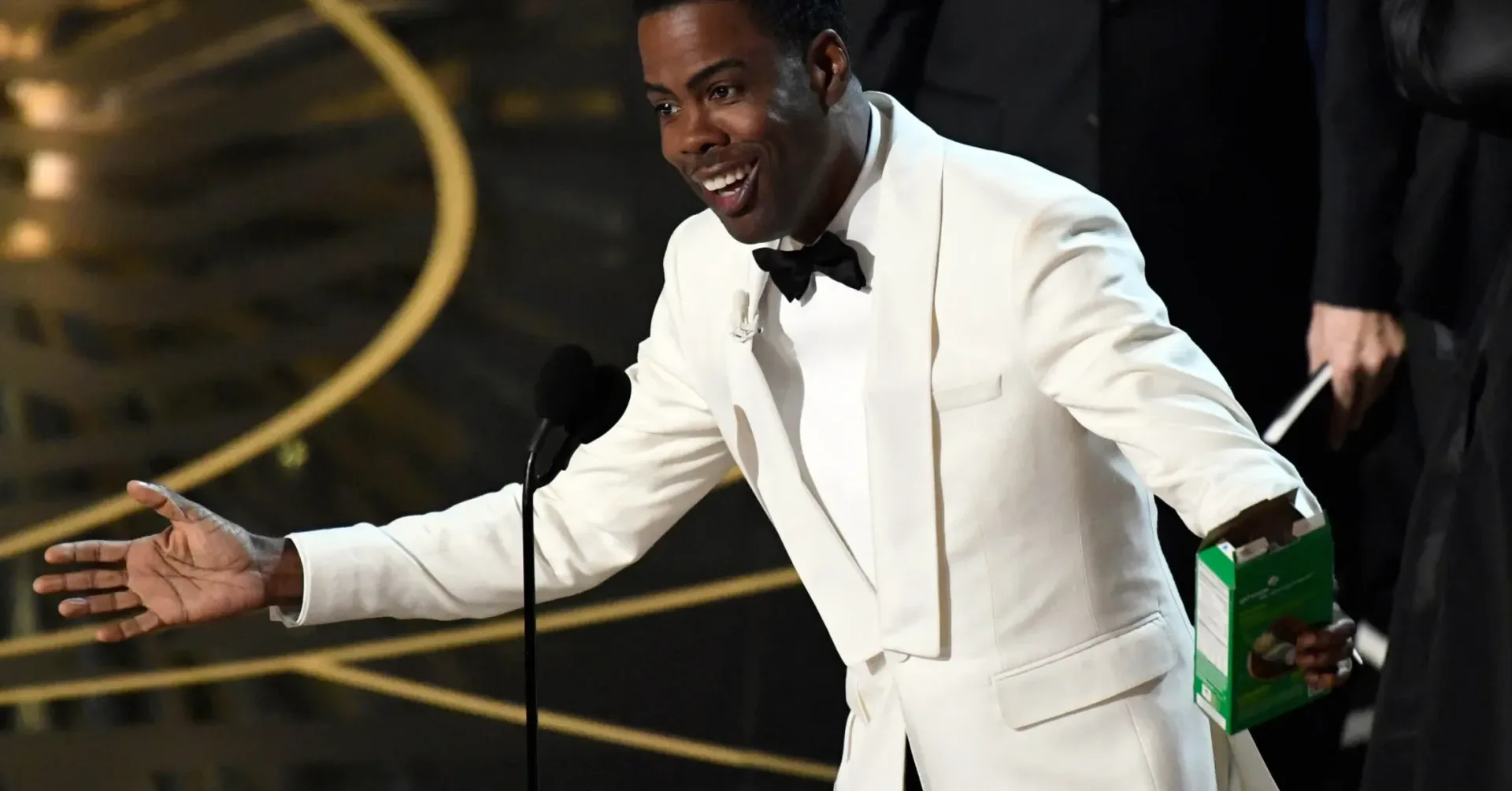 Chris Rock speaking onstage at an awards-show podium