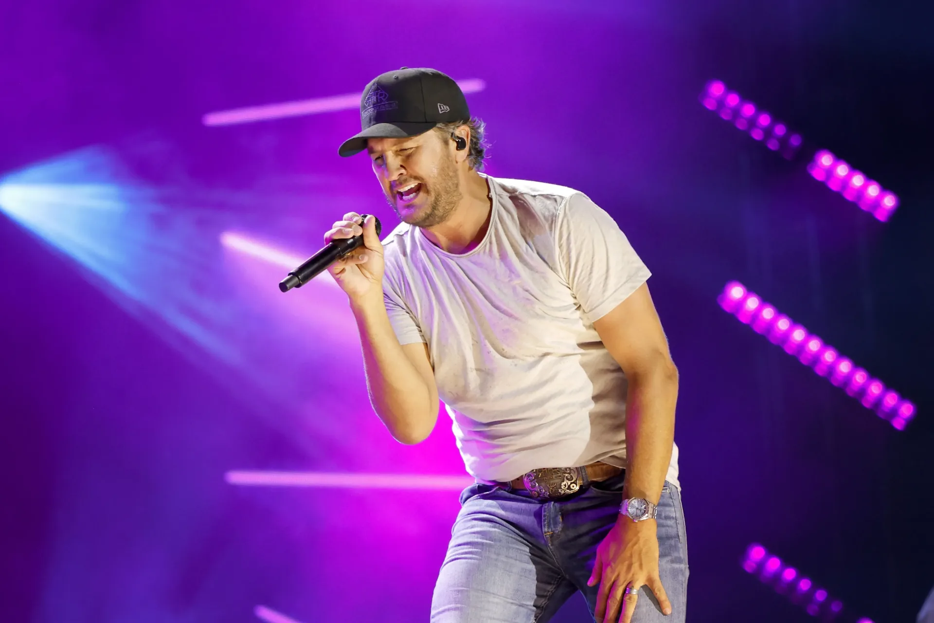 Luke Bryan performing on a stage against Roku City’s animated neon skyline