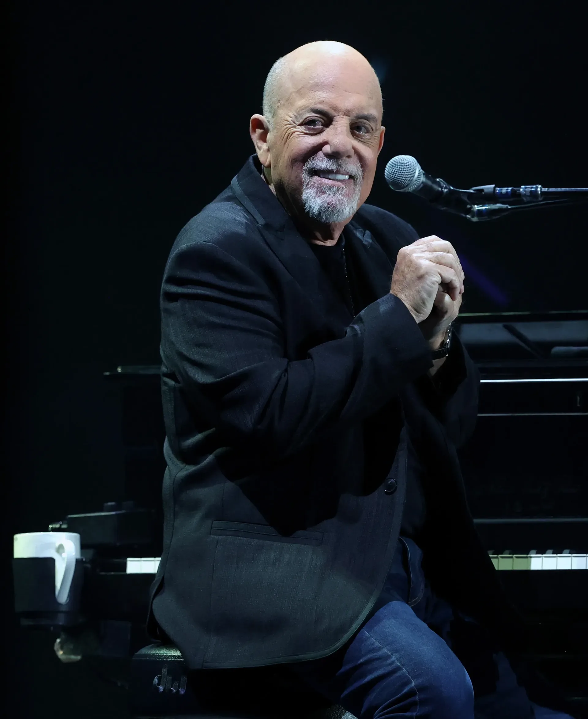 Billy Joel performing at a piano during a live concert