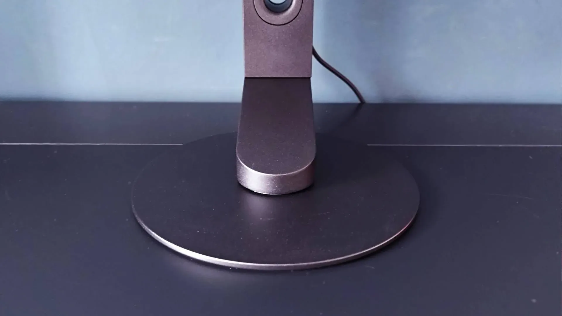 Close up of circular Sony Inzone M10S II stand on black desk.