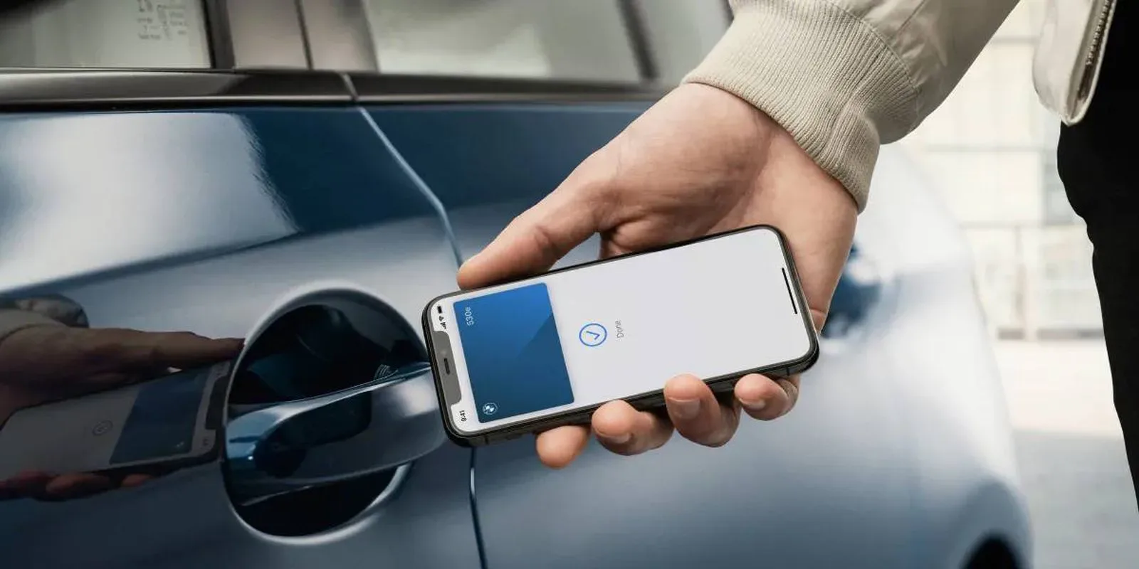 An iPhone displaying an Apple Wallet digital car key beside a vehicle