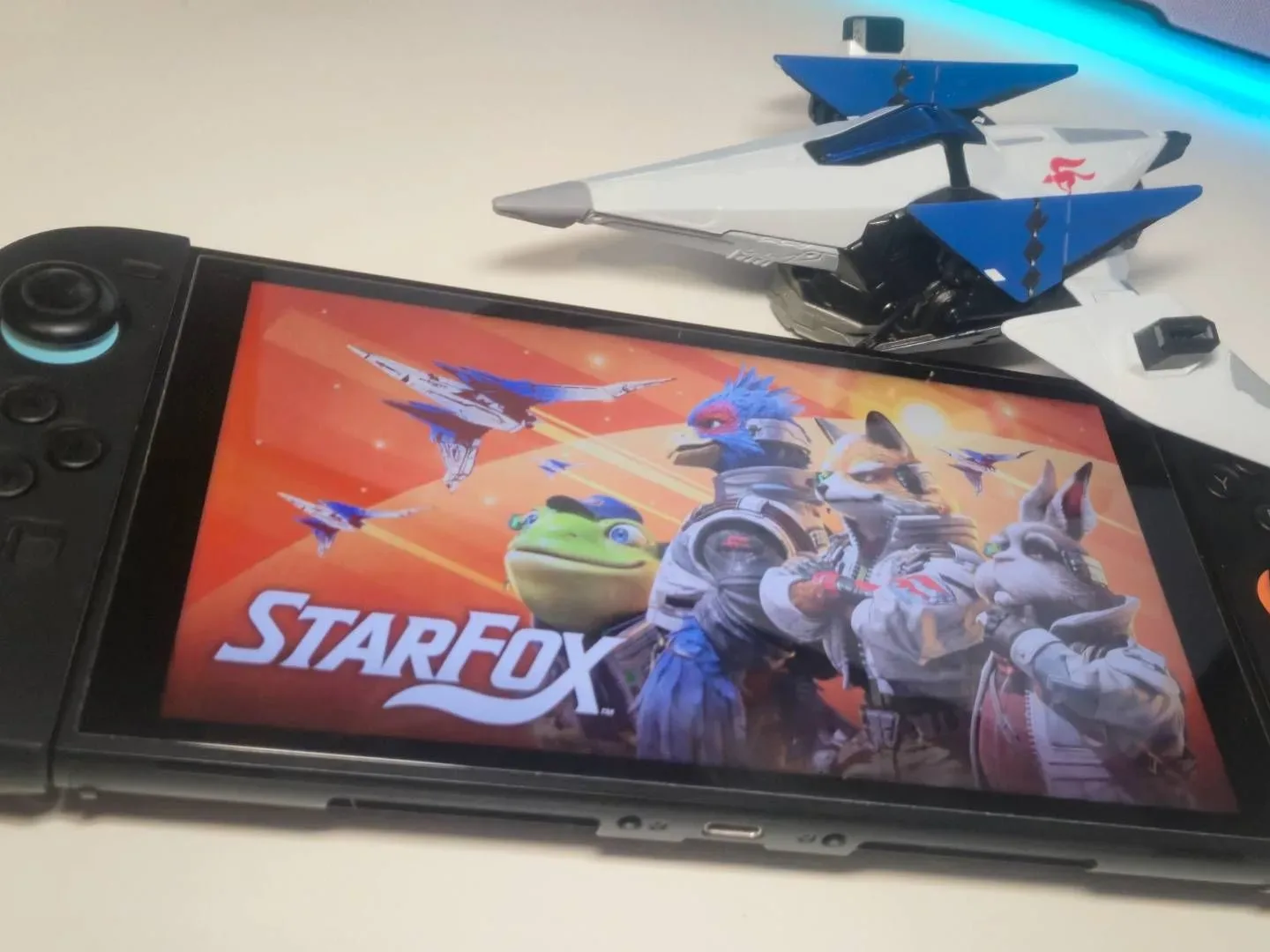 Photo of the key art for Star Fox showing on a Nintendo Switch 2, with a toy Arwing sitting above.