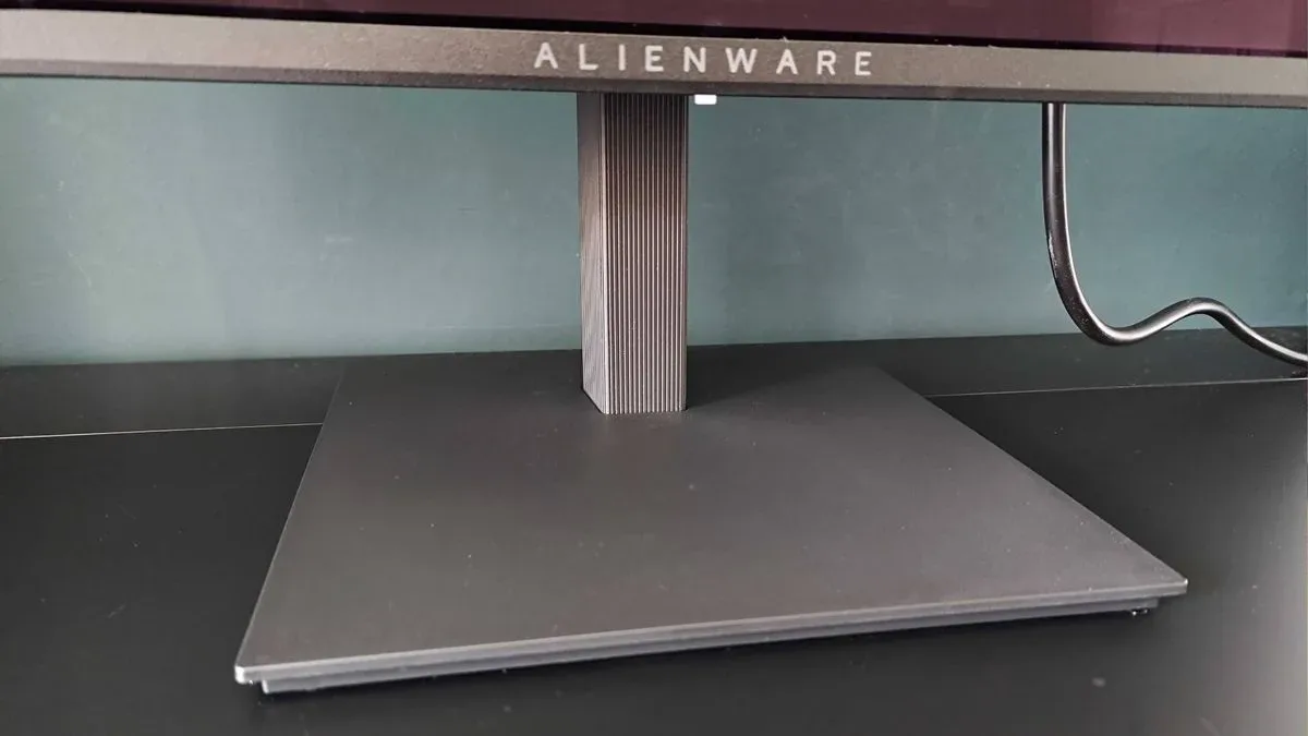Close up of Alienware AW2726DM base stand on black desk.