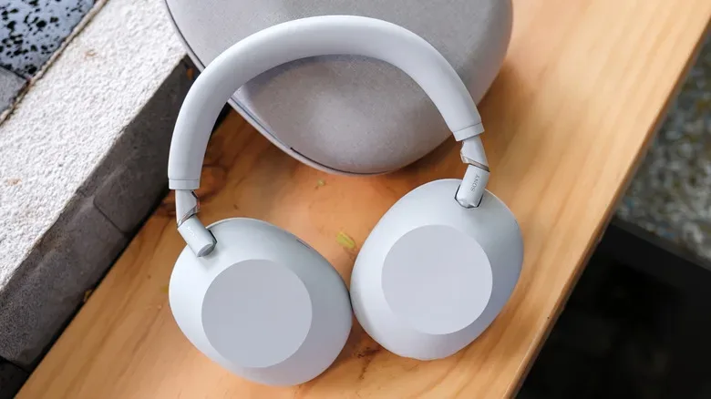 White Sony headphones with ANC on a table next to their case.
