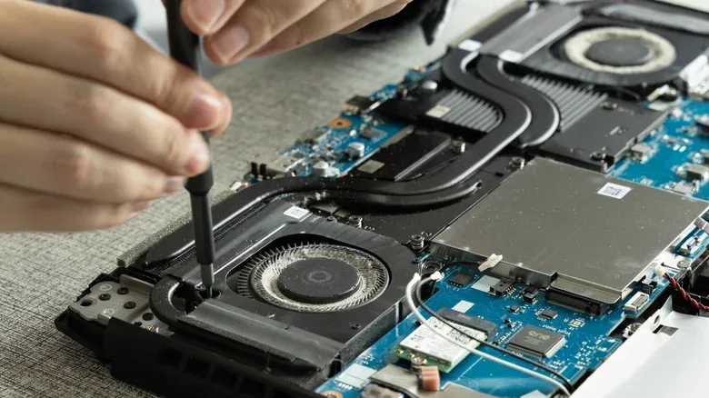 An open laptop with two cooling fans, heat pipes and the motherboard exposed.