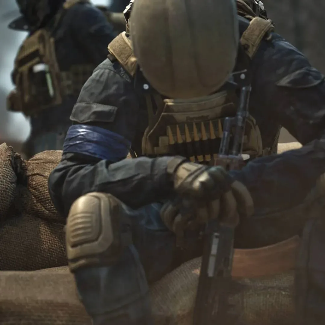 Wardogs solider sitting with hands clasped around rifle