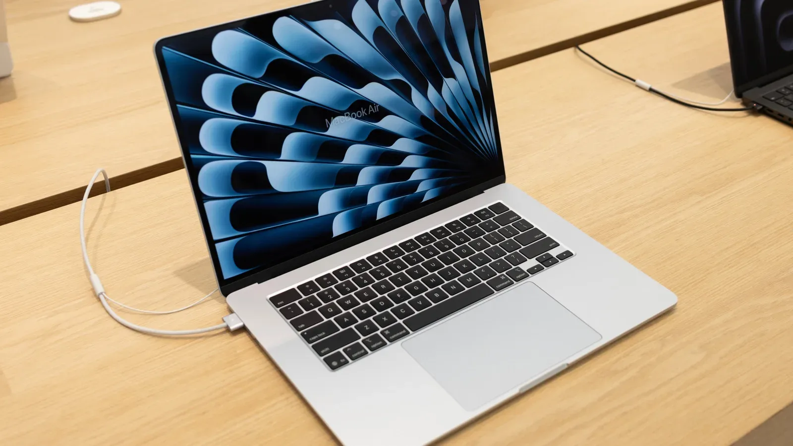 MacBook connected to power on a desk with battery settings open