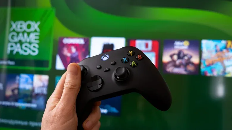 A customer bringing an Xbox console and controller to a retail trade-in counter