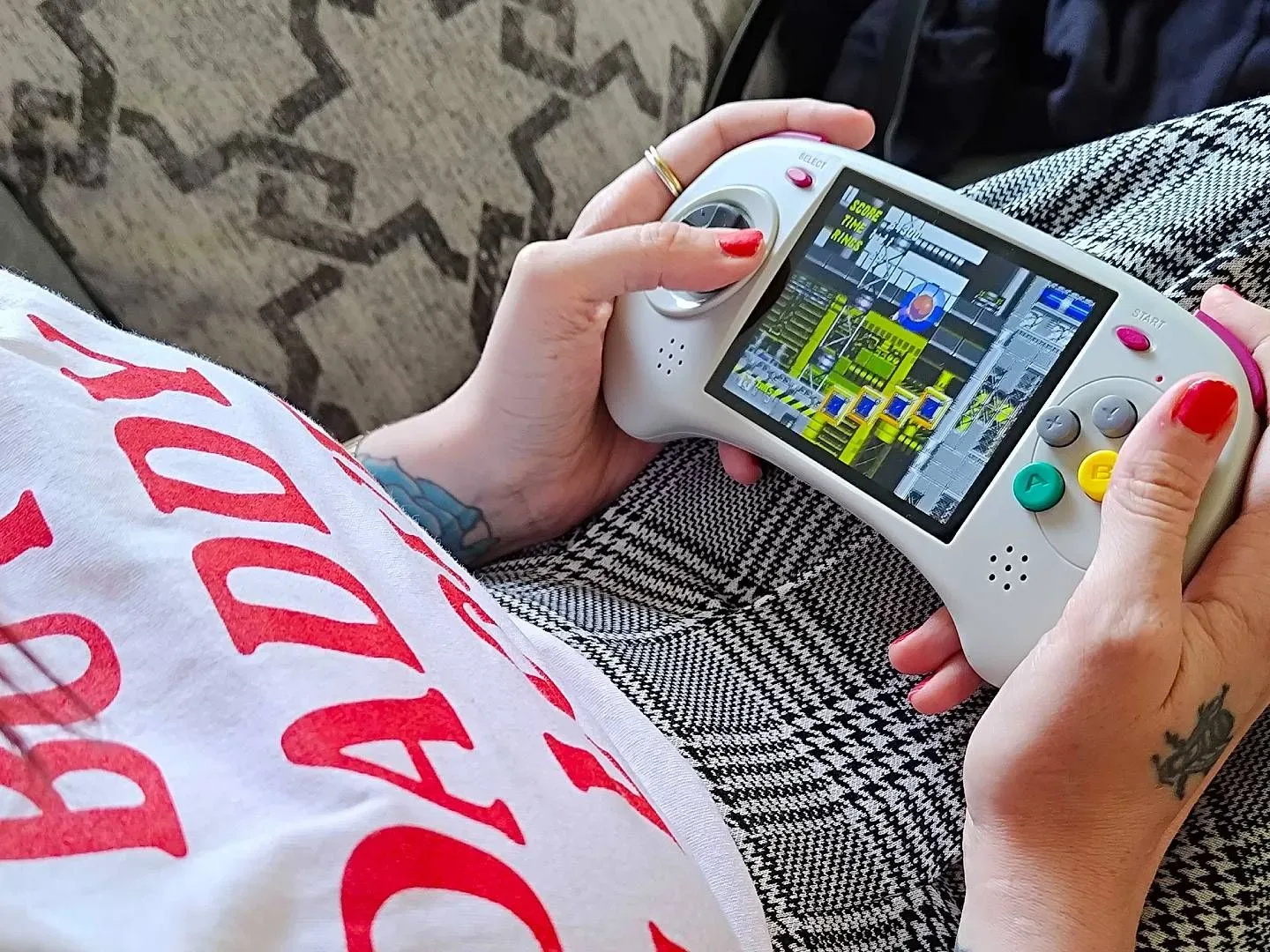 Hands holding Anbernic RG ARC-D with Sonic the Hedgehog 2 gameplay on screen.