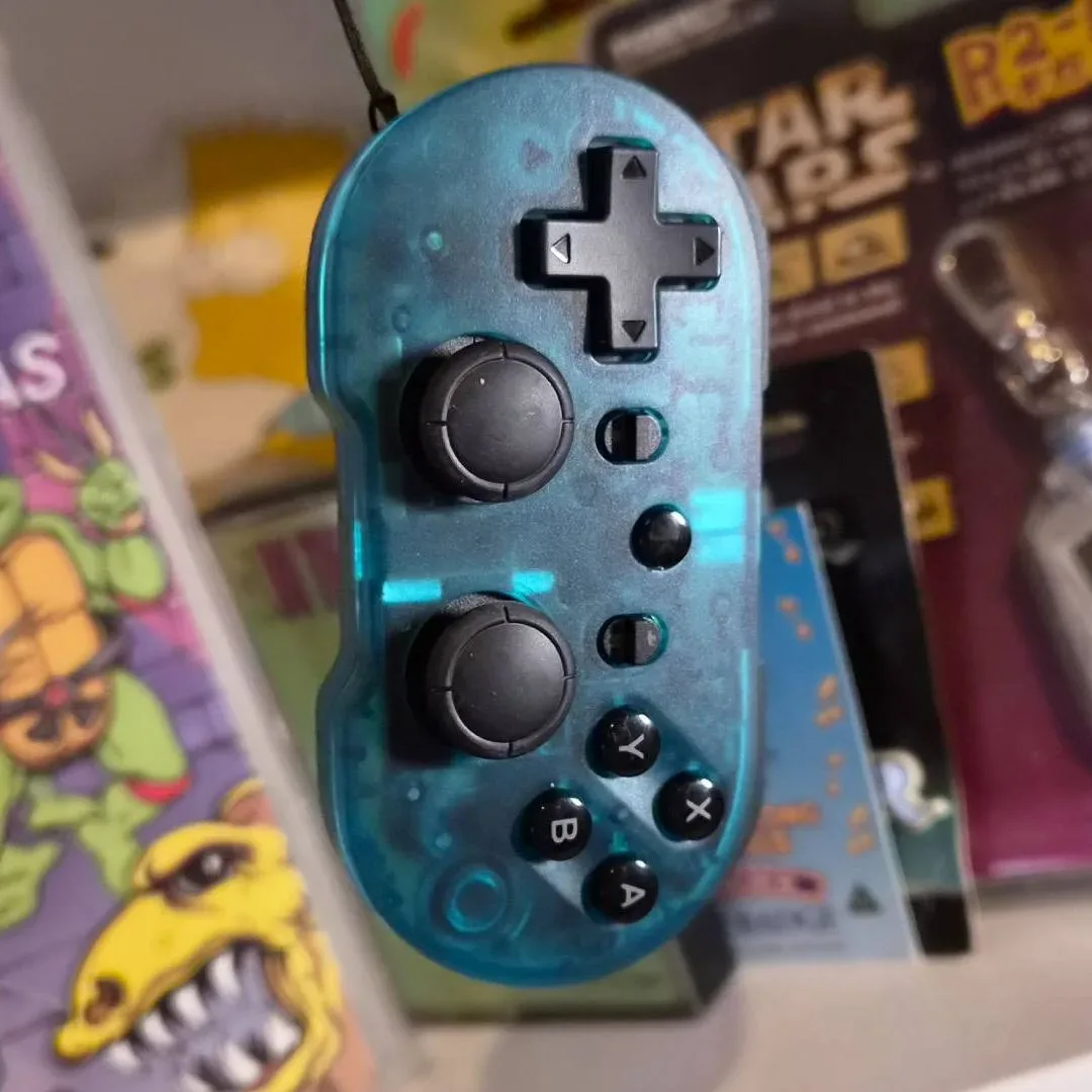 Photo of the CRKD Atom+ controller dangling in front of a shelf.