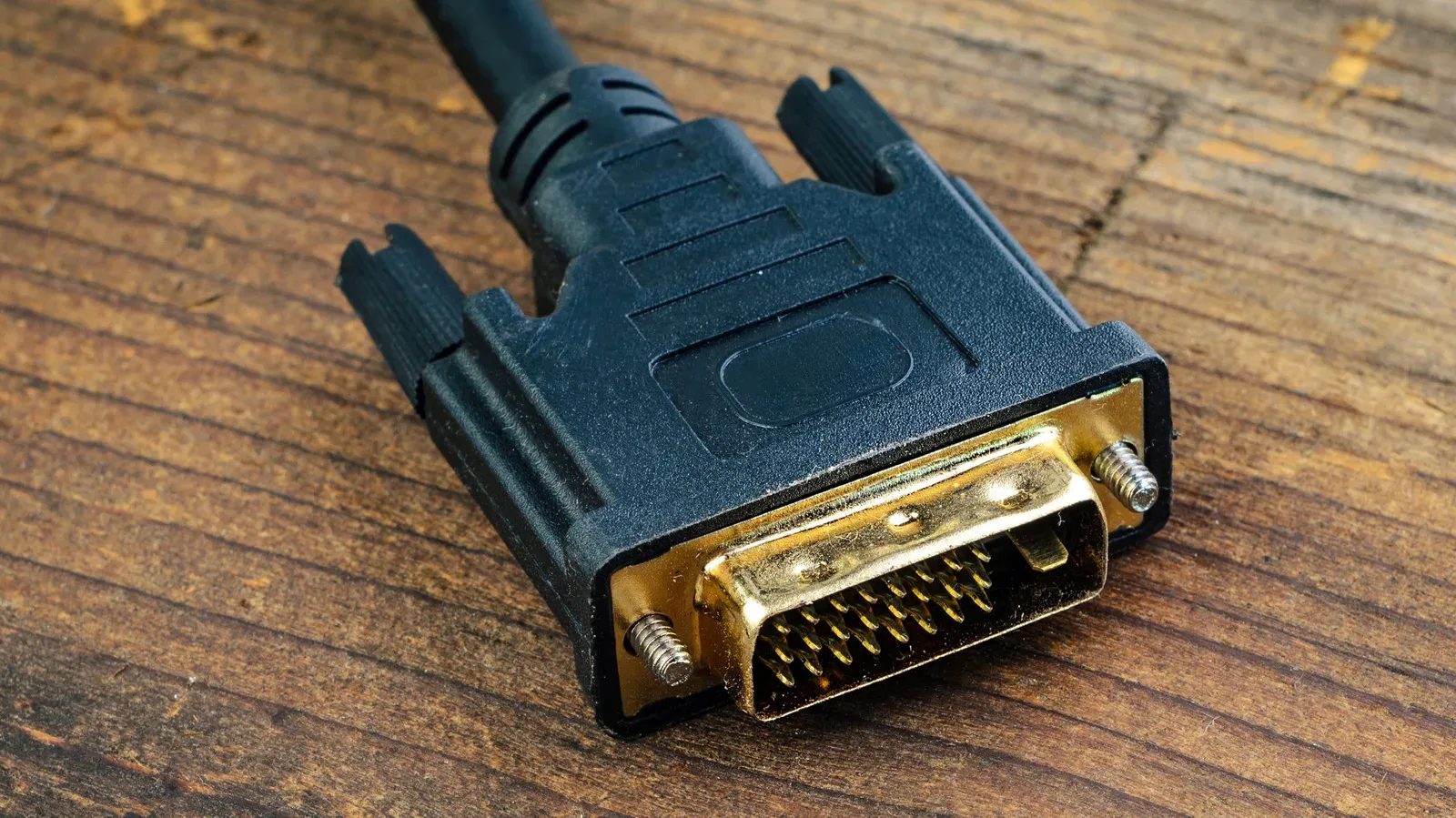 A DVI connector with its pin grid and securing screws beside an HDMI adapter
