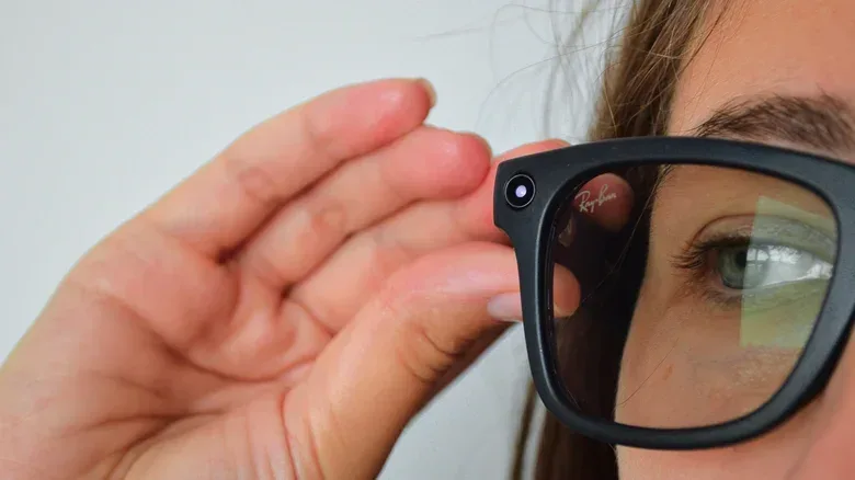Close-up of a woman wearing Ray-Ban Meta smart glasses, with her hand near the built-in camera.