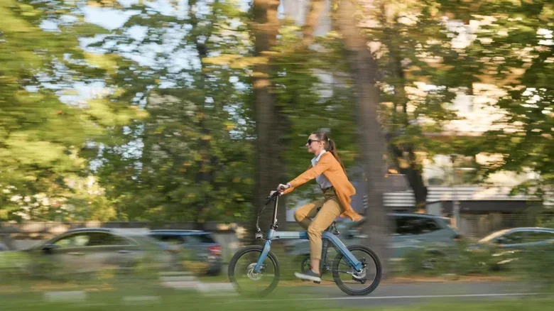 Somebody riding a folding electric e-bike through a park.