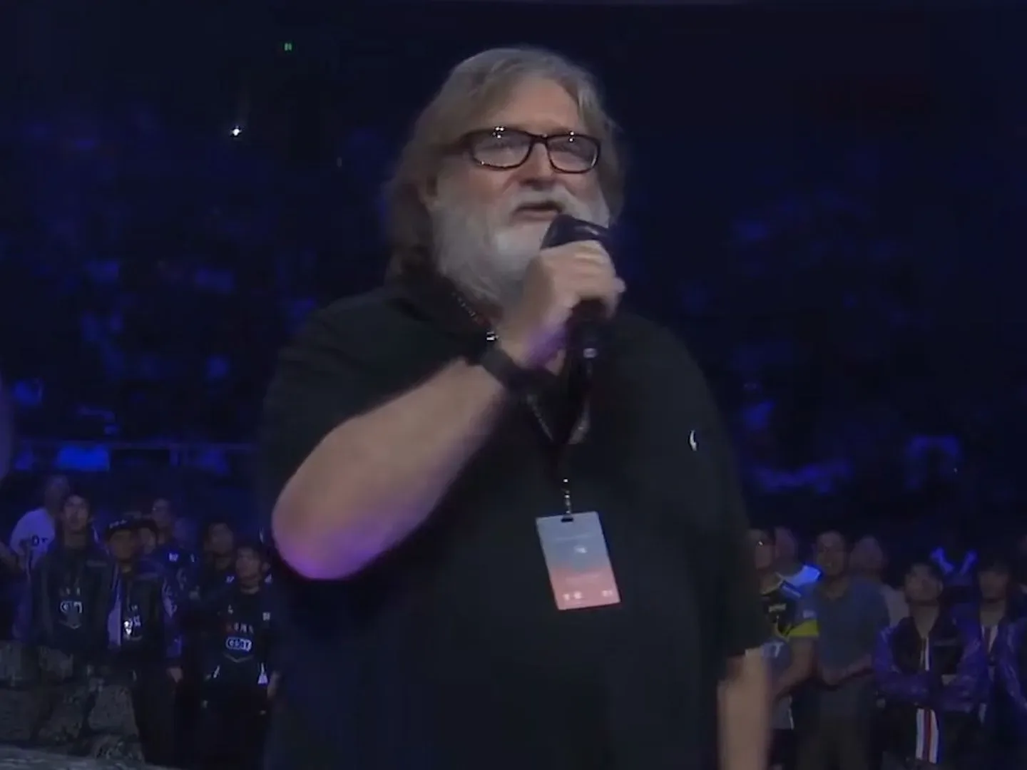 Gabe Newell in a black shirt holding a microphone
