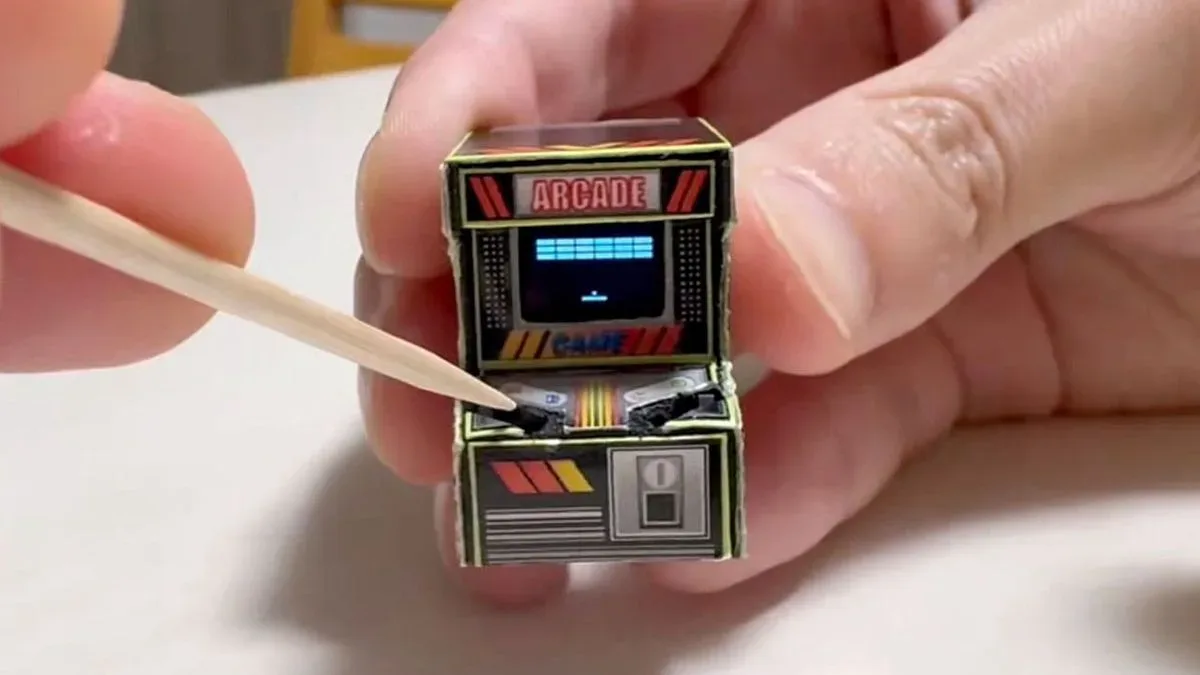 A tiny papercraft arcade cabinet with a working game screen