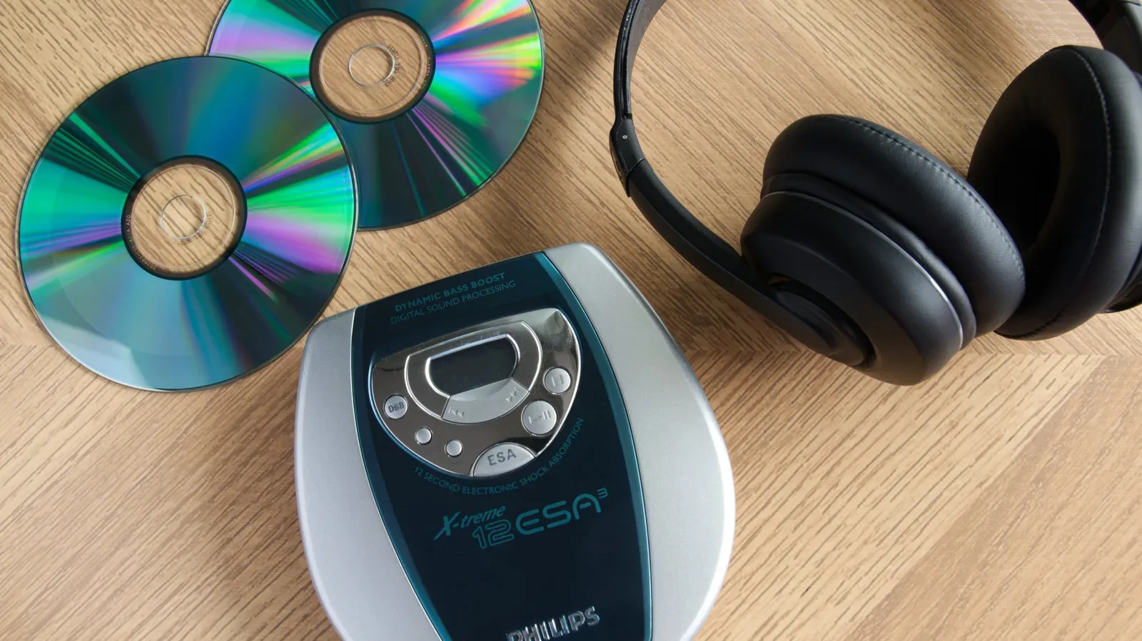 A stack of compact discs beside a modern external USB CD drive