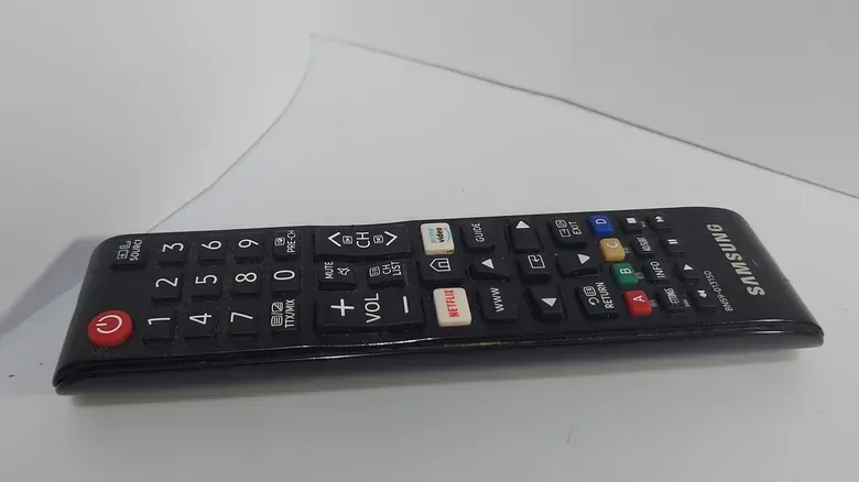 A Samsung remote on a plush white couch.