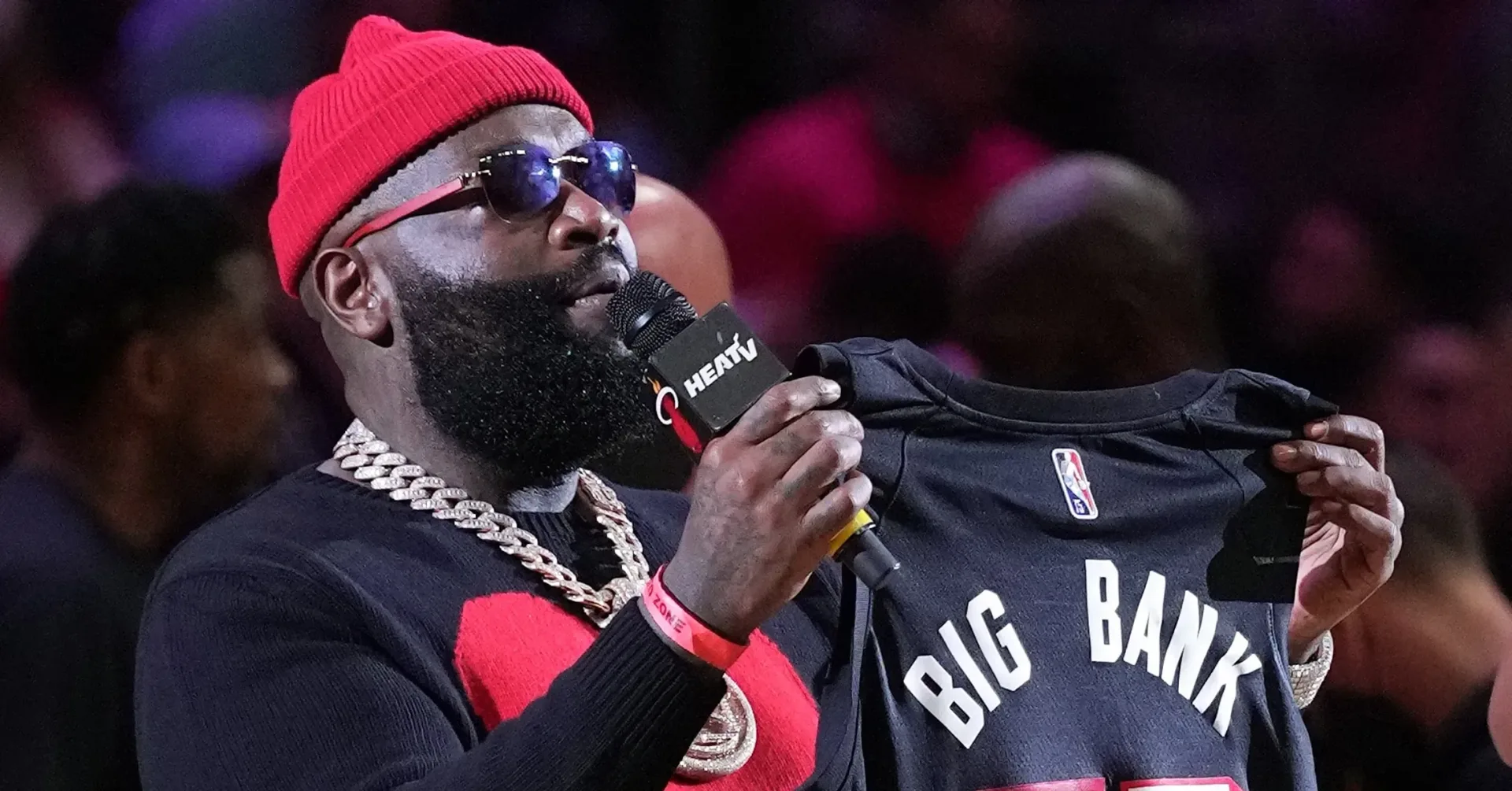 Rick Ross performing onstage under concert lighting