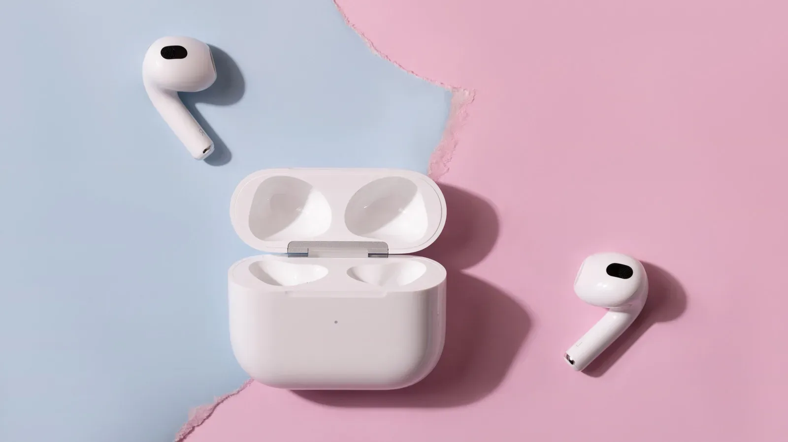 Apple AirPods case beside a Samsung Galaxy phone illustrating cross-platform Bluetooth pairing