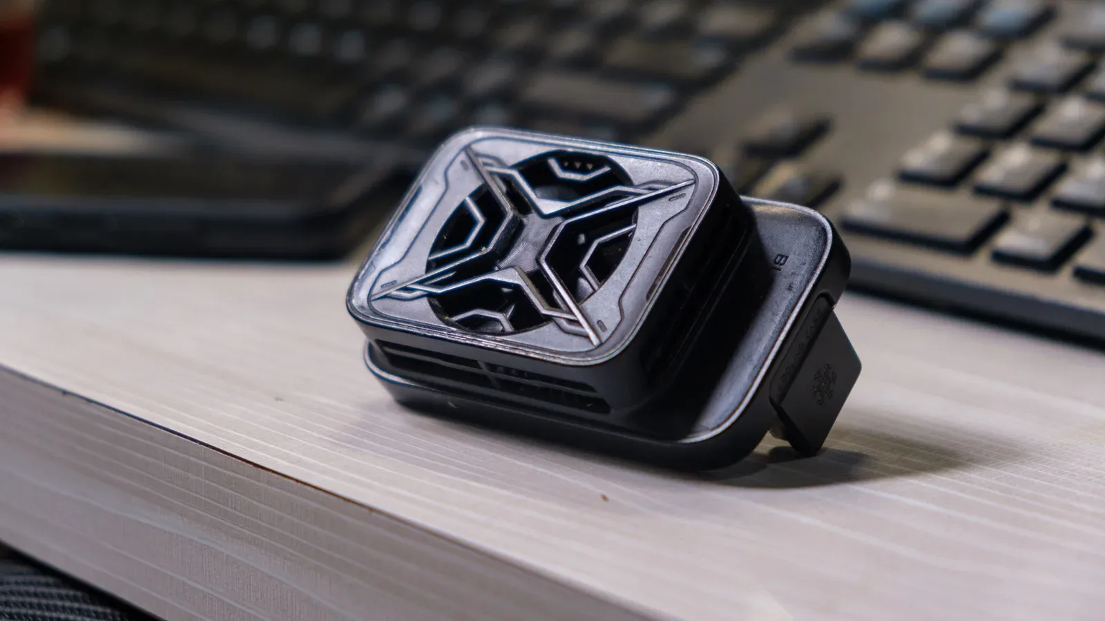 A clip-on active phone cooler attached to the back of a smartphone during mobile gaming