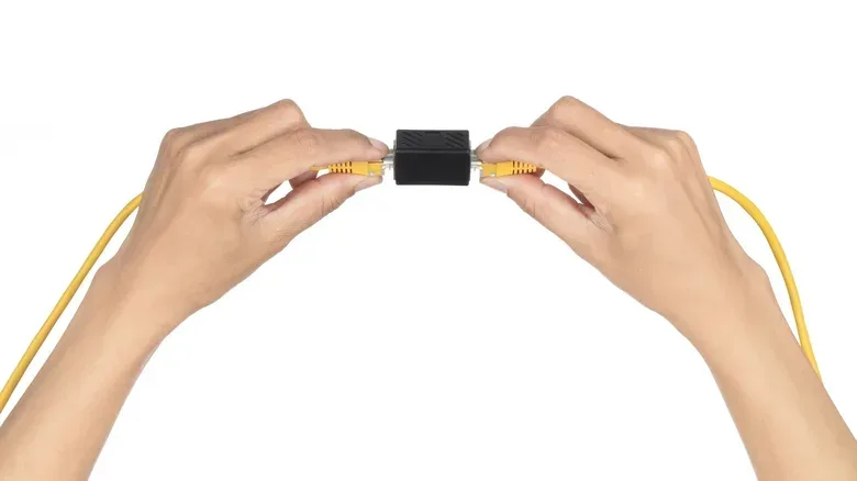 A compact unmanaged five-port Gigabit Ethernet switch beside wired devices