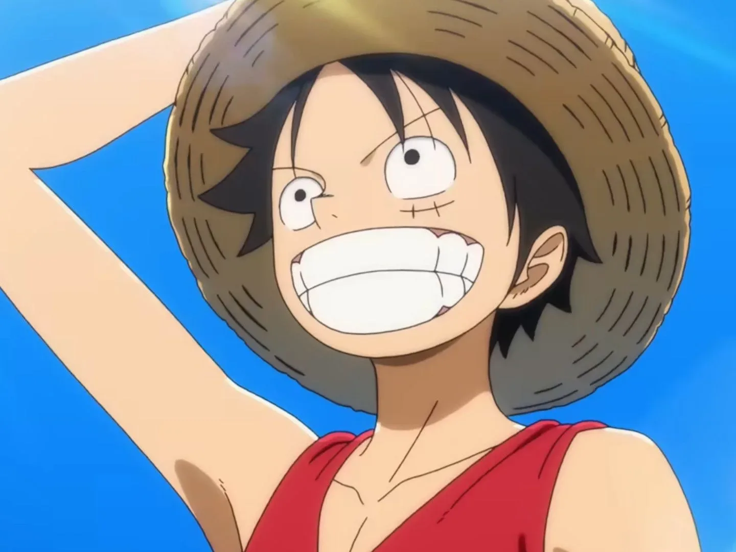 The One Piece explained: A close-up of Luffy smiling while holding his hat in a screenshot of the upcoming reboot, The One Piece
