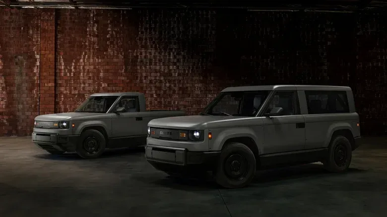 A Slate Truck and SUV stand in a shadowy, brick-walled warehouse.