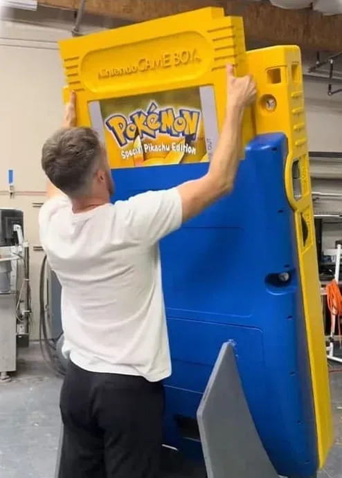 Giant Pokémon Yellow cartridge being inserted into the oversized Game Boy Color